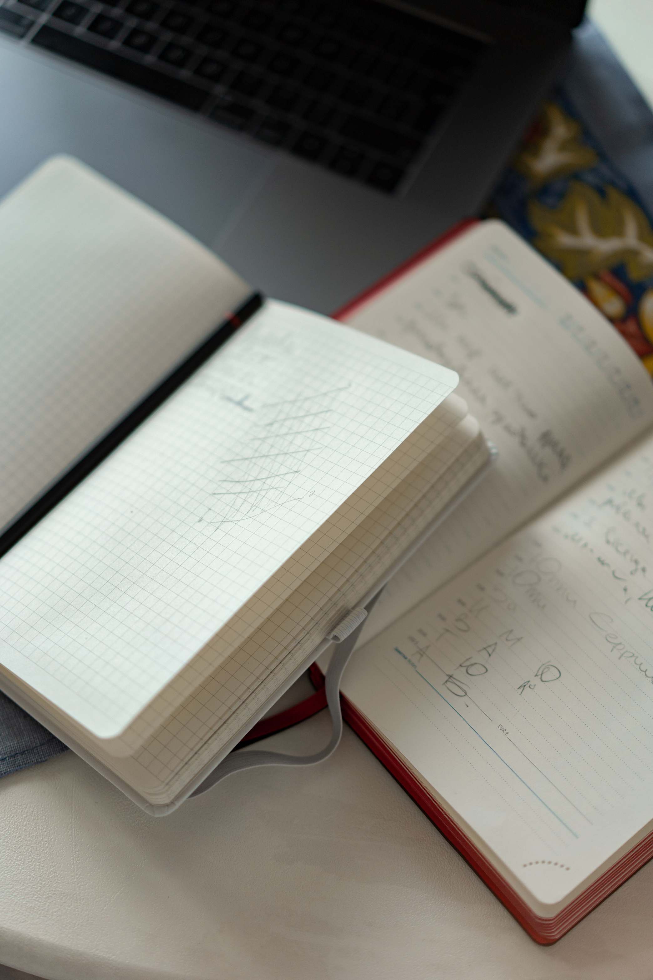 Laptop mit Tabellenkalkulation auf einem Schreibtisch, Notizbücher und Laptop auf weißem Schreibtisch